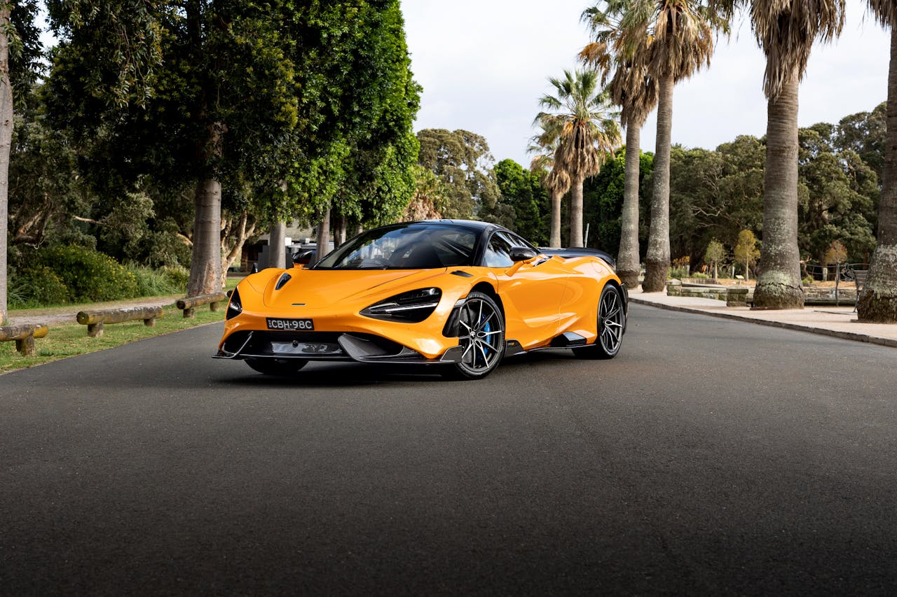 Stunning orange McLaren 765LT captured on a picturesque road in Sydney, exuding speed and luxury.